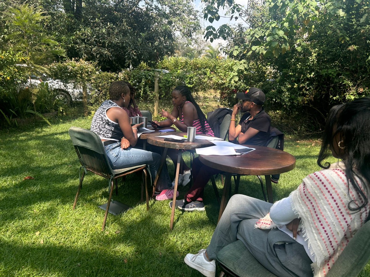 A small group in an outdoor research session, reviewing notes around a table.
