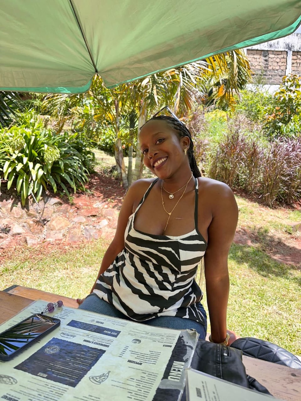 Diana smiling at an outdoor cafe table under a green umbrella.