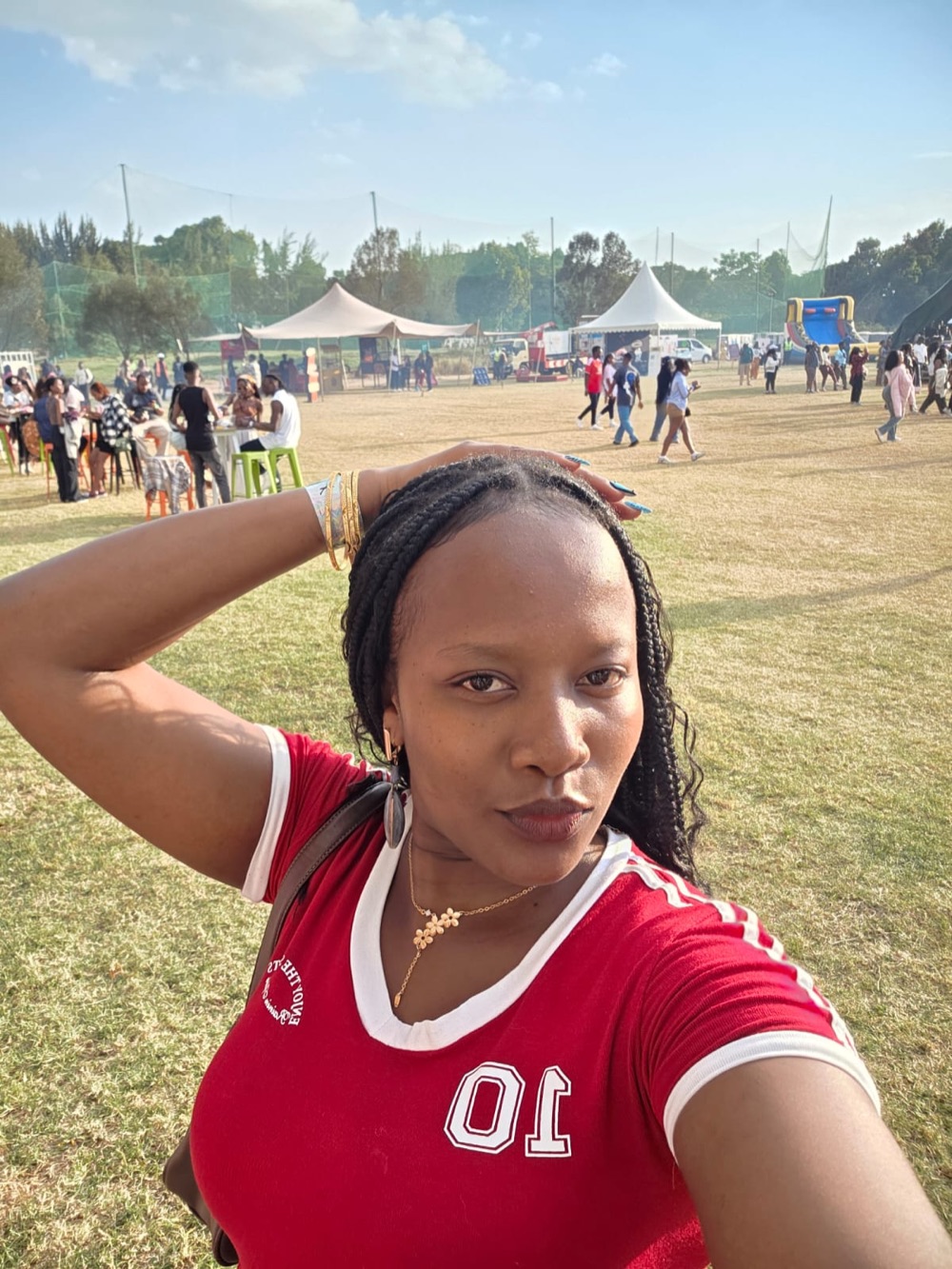 Diana taking a selfie in a red jersey at an outdoor community event.