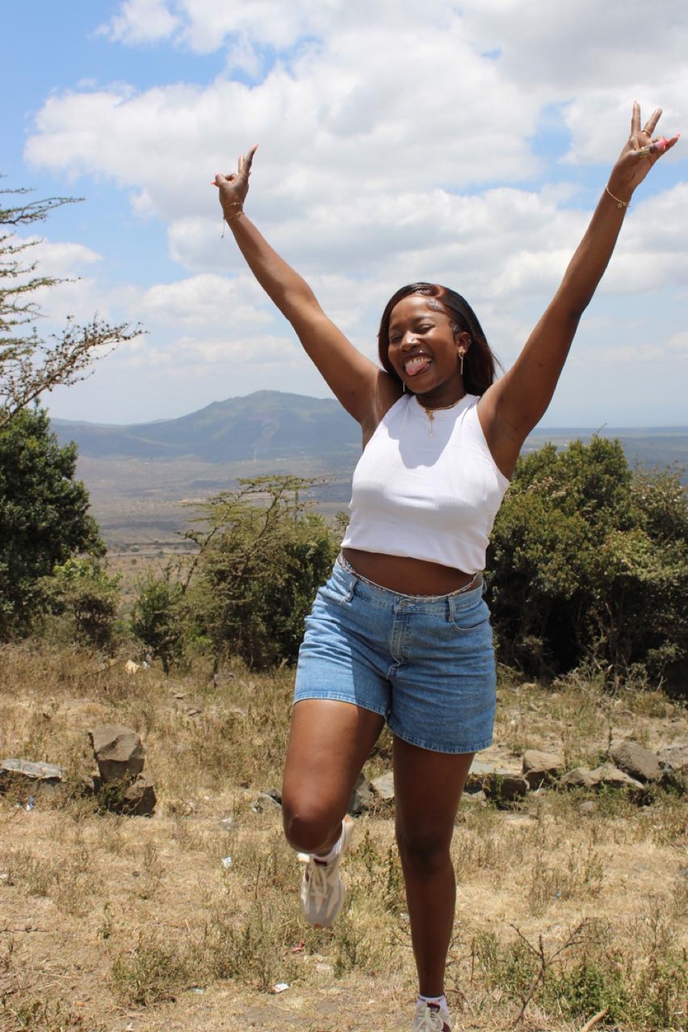 Diana jumping with arms raised on a hilltop overlooking the Rift Valley.