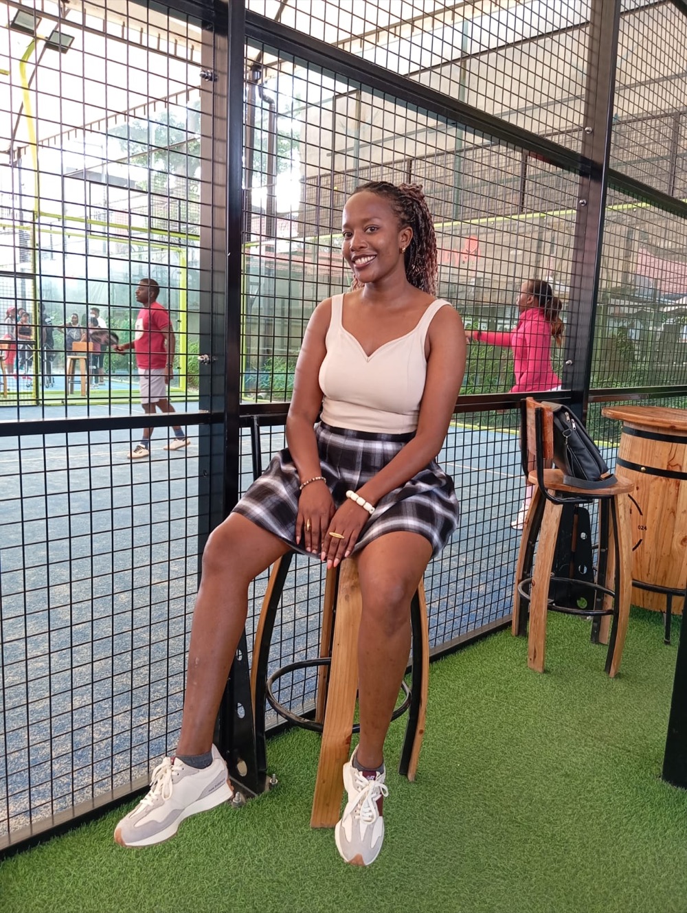 Diana sitting courtside at an outdoor padel court.