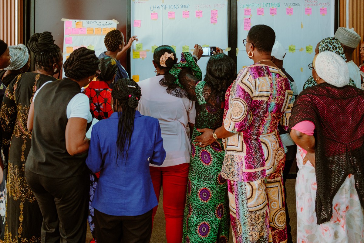 Diana facilitating a co-design workshop with a group gathered around a wall of sticky notes.